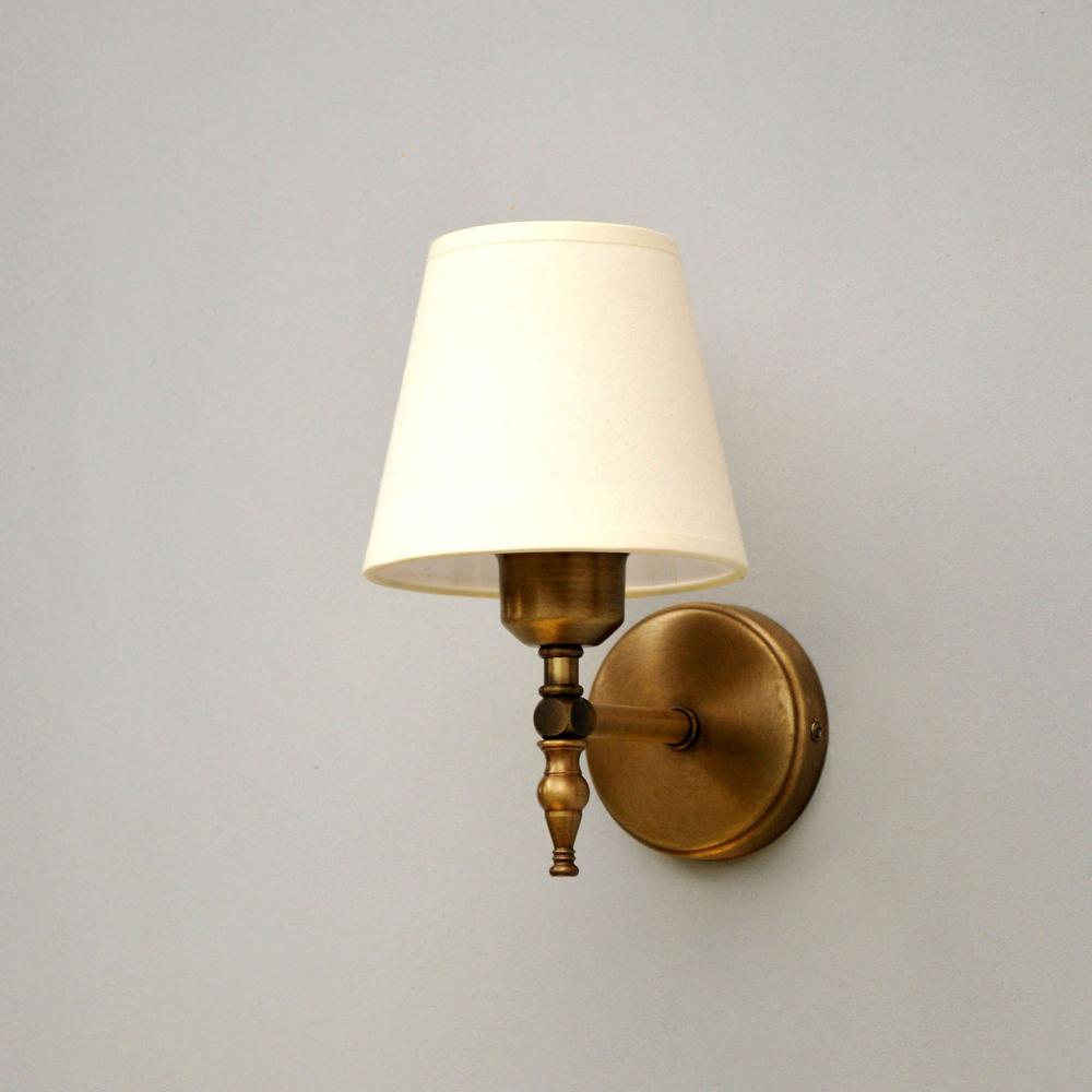 Eskitme gold duvar apliği, krem kumaş başlığı ve kubbemsi detay tasarımıyla klasik zarafeti modern iç mekânlara taşır.