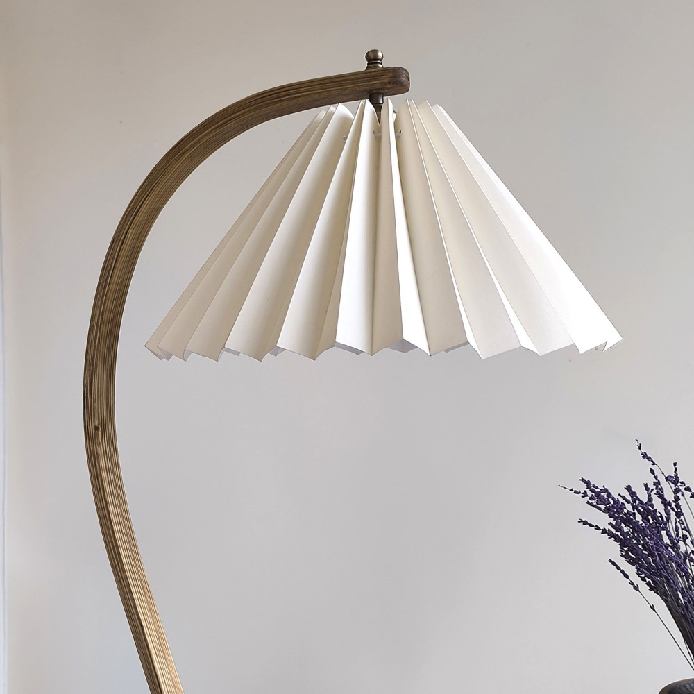 El yapımı kavisli masif ahşap gövdeli Sillon lambader – 45 cm pileli krem başlığı ve beyaz opak iç yüzeyiyle modern, doğal ve zarif bir atmosfer oluşturur.